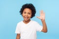 Portrait of amazing friendly little boy grinning happily and waving hi, gesturing hello with raised arm, welcoming greeting