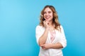 Portrait of amazing happy woman touching chin while thinking, dreaming with joyous smiling face. blue background