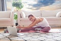 Portrait of amazing young beautiful fitness woman make stretching exercises indoors at home near laptop computer Royalty Free Stock Photo