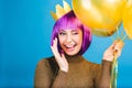 Portrait amazing young woman celebrating carnival, great party on blue background. Cut purple hair, pink tinsels makeup Royalty Free Stock Photo