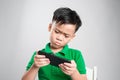 Portrait of an amused cute little kid playing games on smartphone isolated over gray background