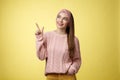 Portrait of amused interested cute 20s european girl wearing sweater, headband looking upper left corner pointing