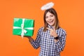 Portrait of angelic positive brunette woman with charming smile holding presents. isolated on orange background