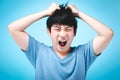 Portrait of angry asian kid on blue background