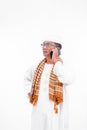 Portrait of smiling asian muslim old man wear white clothes  talking on a smartphone and raise one arm isolated over white Royalty Free Stock Photo