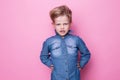 Portrait of angry beautiful little boy. Studio portrait over pink background