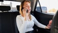 Portrait of angry blonde businesswoman shouting while having a talk by phone in a taxi car Royalty Free Stock Photo