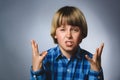 Portrait of angry boy in blue shirt with hands up yelling isolated on gray studio background. Negative human emotion Royalty Free Stock Photo