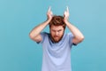 Man showing bull horn gesture with fingers over head looking hostile and threatening aggressive face Royalty Free Stock Photo