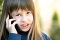 Portrait of angry child girl with long hair talking on cell phone. Little female kid having discussion on smartphone. Children Royalty Free Stock Photo