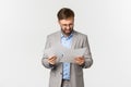 Portrait of angry and confused businessman in grey suit, looking at documents or bad report, standing disappointed over