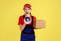 Courier woman holding box and screaming in megaphone, looking at camera with aggressive expression. Royalty Free Stock Photo