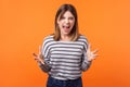 Portrait of angry, crazy young woman with brown hair in long sleeve shirt. isolated on orange background