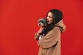 Portrait of an angry dissatisfied woman yelling at her scared doggy - york terrier, standing in front of the red wall. Isolated Royalty Free Stock Photo