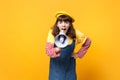 Portrait of angry girl teenager in french beret, denim sundress scream in megaphone, swearing isolated on yellow