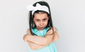 Portrait of the angry little girl wearing blue dress and white bow with crossed arms posing over white background. Displeased Royalty Free Stock Photo