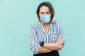 Portrait of angry middle aged woman with surgical medical mask standing with crossed arms and looking at camera frowning Royalty Free Stock Photo