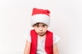 Portrait of angry resentful little child in red Santa Claus hat isolated on white background. Beautiful five-year European boy.