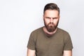 Portrait of angry sad bearded man with dark green t shirt against light gray background. Royalty Free Stock Photo