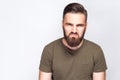 Portrait of angry sad bearded man with dark green t shirt against light gray background. Royalty Free Stock Photo