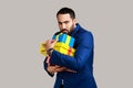 Portrait of angry serious bearded man holding stack of presents in hands being greedy to share gifts