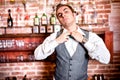 Portrait of angry and stressed barman with bowtie behind the bar