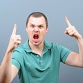 Portrait of a angry threatening man screaming against gray background