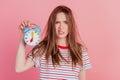 Portrait of angry tired cute lady aggressive face hold clock look camera on pink background