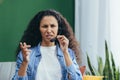 Portrait of angry woman with headset at home, Hispanic woman working remotely as consultant, looking displeased at