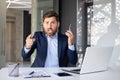 Portrait of an angry young man businessman sitting in the office at the table, talking on the phone, shouting and Royalty Free Stock Photo