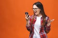 Portrait of an angry young woman shouting at a mobile phone, isolated on a orange background Royalty Free Stock Photo