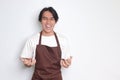 Portrait of annoyed Asian barista man in brown apron making angry hand gesture with fingers Royalty Free Stock Photo