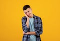 Portrait of annoyed Caucasian guy in casual wear looking at camera in frustration, orange studio background