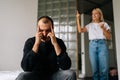 Portrait of annoyed serious husband sitting on bed looking away ignoring angry wife arguing blaming upset man of Royalty Free Stock Photo