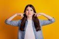 Portrait of annoyed woman fingers close ears look empty space on yellow background