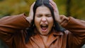 Portrait annoyed young hispanic woman outdoors screaming loudly in rage madly opening mouth holding hands on head Royalty Free Stock Photo