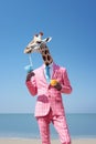 portrait of a Anthropomorphic cute giraffe in a pink suit and glasses with a cocktail in his hands on the beach against the sky.