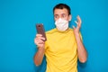 Portrait anxious young man in medical mask against virus looking at phone seeing bad news or photos with disgusting emotion on