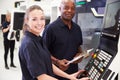 Portrait Of Apprentice Working With Engineer On CNC Machine