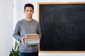 Portrait of arabic male teacher with books blackboard background. Back to school concept, education and knowledge