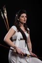 Portrait of a archer woman in white dress with bow and arrow on black background. Greek goddess Artemis. Studio photo shoot. Royalty Free Stock Photo