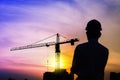 Portrait of architect silhouette wear a helmet at construction site with crane background and sunset Royalty Free Stock Photo