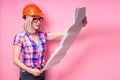 Portrait of architect student blonde woman in helmet with blueprints protect in the studio on a pink background.designer Royalty Free Stock Photo