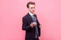 Portrait of arrogant rich businessman showing bunch of dollars on camera. indoor studio shot isolated, pink background Royalty Free Stock Photo