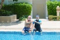 Portrait asia senior woman and caucasian old man resting together in the edge of swimming pool in clubhouse Royalty Free Stock Photo