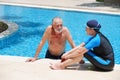 Portrait asia senior woman and caucasian old man resting together in the edge of swimming pool in clubhouse Royalty Free Stock Photo
