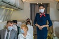 Air hostess standing with passengers sitting in plane with wearing face mask