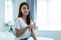 Portrait of Asian attractive woman holding a glass of water in bedroom. Young thirsty beautiful girl carry clean mineral natural