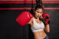 Portrait of asian attractive woman wearing red boxing gloves with workout and pose boxing show on right punch in gym Royalty Free Stock Photo