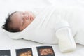 Portrait of Asian Australian newborn baby less than one month old wrapped with cotton towel sleeping on bed with fetal ultrasound Royalty Free Stock Photo